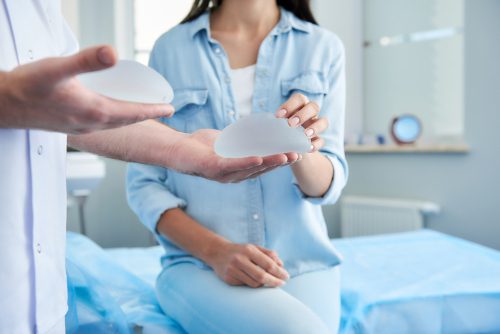 doctor holding in his hands two silicone implants. Female patient trying to touch them-img-blog