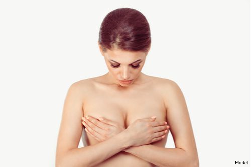 Woman clutching her breasts contemplating breast implant removal