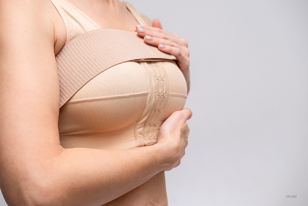 Woman in a tan bra with a tan strap over her breasts